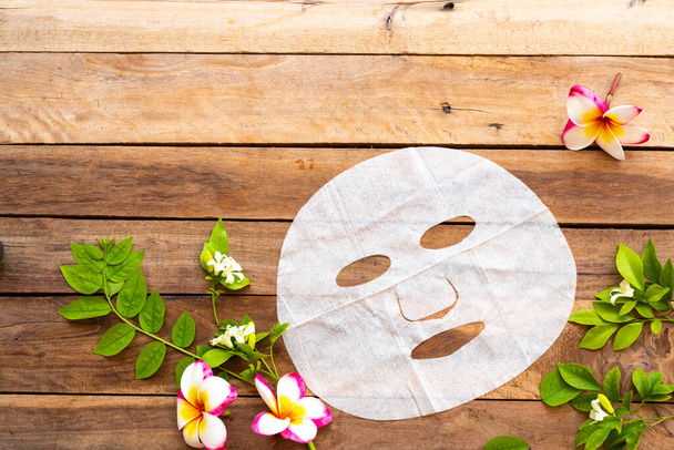 naturalny aromat maska wyciąg ziołowy esencja maska twarzy ochrona zdrowia dla skóry twarz z kwiatów frangipani, układ liści płaski styl układania na tle drewniane - Zdjęcie, obraz