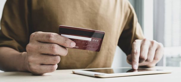 La mano del hombre de negocios sostiene una tarjeta de crédito y usa un teléfono inteligente para comprar en línea y pagar por Internet en la oficina. - Foto, Imagen