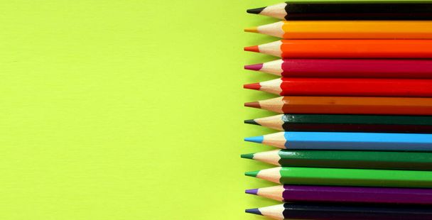 Colored pencils on a yellow background. Lots of different colored pencils. Colored pencil. Pencils are sharp. Pencils are on the left. Close-up. Copy space. Background. Flat lay. - Photo, image
