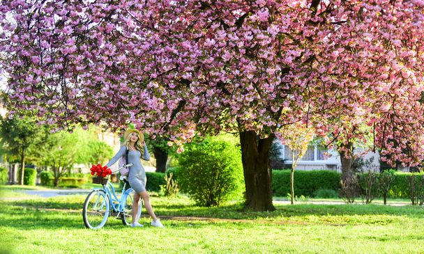 Eco lifestyle. Eco transportation. Excursion to garden. Athletic woman ride retro bicycle. Travel by bike. Spring holidays. Riding bicycle. Girl and sakura blossom. Cycling Tours. United with nature - Photo, image