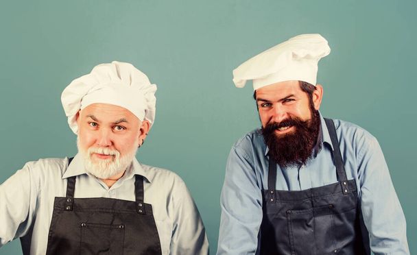Restaurant staff. Father and son culinary hobby. Family restaurant. Mature bearded men professional restaurant cooks. Chef men wear aprons. Cafe workers. Restaurant kitchen. Culinary industry - Фото, изображение