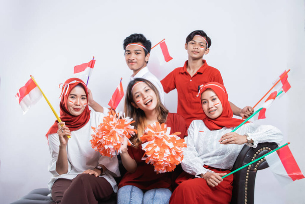 group of friends smiling holding a pompom and small flags while wearing the Indonesian flag - Photo, Image