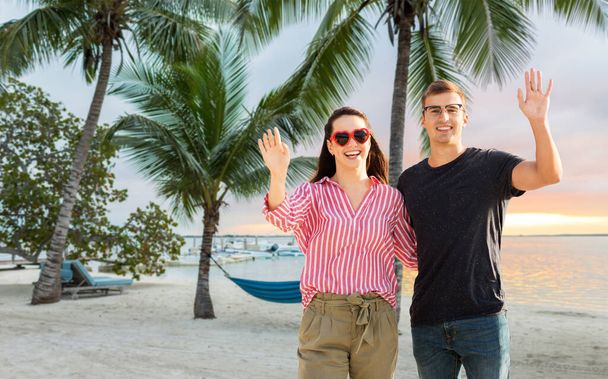 happy couple waving hands on beach - Valokuva, kuva