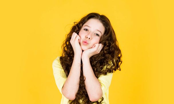 Young and carefree. hairdresser for child. shampoo cosmetic for hair. happy childrens day. little beauty with stylish look. small girl with long curly hair. fashion model kid has brunette hairstyle - Fotó, kép