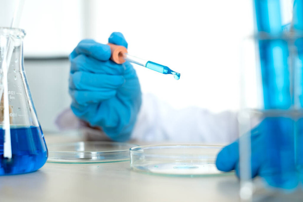Les scientifiques médicaux ont libéré un échantillon pipetté dans la verrerie d'essai pour analyser le virus dans un laboratoire chimique. Concepts de recherche scientifique. - Photo, image