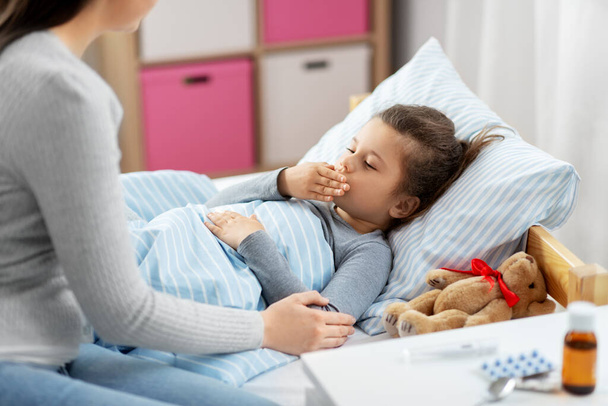 mother and sick little daughter in bed at home - Foto, Imagem