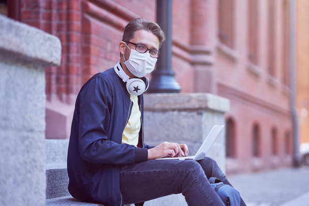 Mies opiskelija kampuksella yllään naamio johtuu sepelvaltimovirus pandemia - Valokuva, kuva