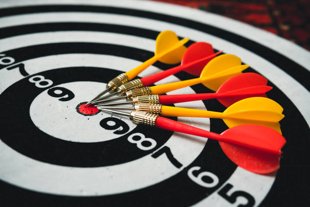 Close red and yellow dart on target board right frame. yellow and red Darts lie on a black and white target - Photo, Image