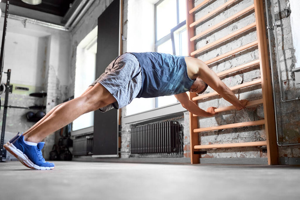 man exercising on gymnastics wall bars in gym - Photo, image