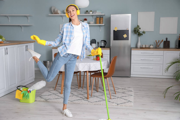 Giovane donna si diverte mentre pulisce la cucina - Foto, immagini