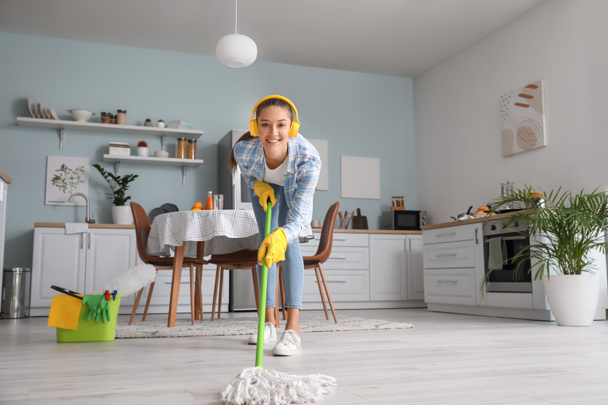 Молода жінка розважається під час прибирання кухні
 - Фото, зображення