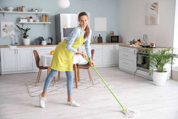 Beautiful young woman cleaning kitchen - Foto, Bild