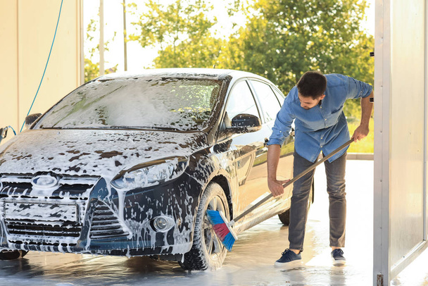 Чоловік миє машину на відкритому повітрі
 - Фото, зображення