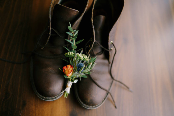Um close-up de botões para o noivo e homens sapatos em um fundo marrom
. - Foto, Imagem
