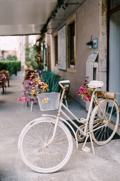 Decorative white bicycle with wildflowers in a basket on the white floor in the hall. - 写真・画像