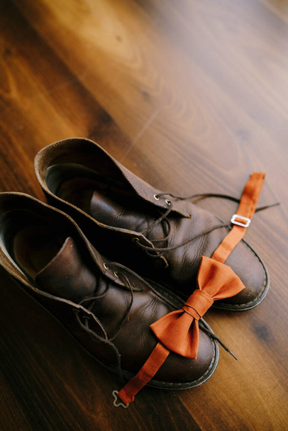 Kahverengi çizmeli, bağcıkları çözülmüş damat için turuncu papyon.. - Fotoğraf, Görsel