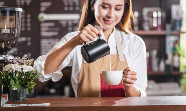 Asian Barista wylewanie mleka do filiżanki kawy, która jest espresso z latte lub cappuccino na zamówienie klienta w kawiarni, Właściciel małych firm i startup w kawiarni i restauracja concep - Zdjęcie, obraz