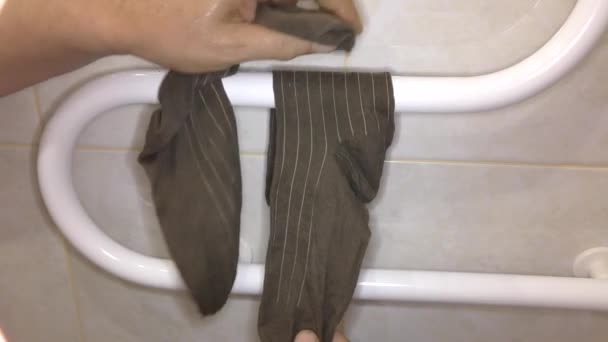 L'homme sèche des chaussettes sur une bobine de séchage. - Séquence, vidéo