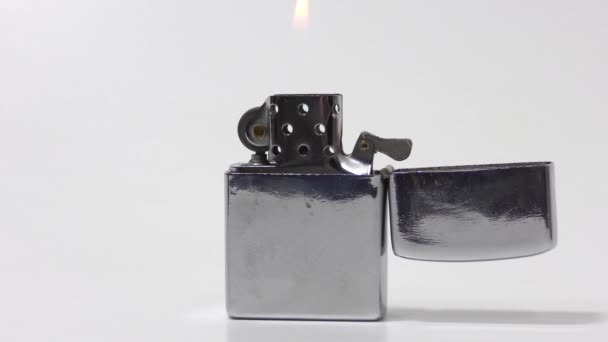 Освещённая металлическая зажигалка на белом фоне - Кадры, видео