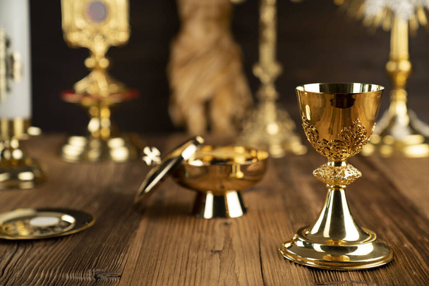 Katholieke religieuze symbolen. Kruis, monstrans, Jezus gestalte, Bijbel en gouden kelk op het rustieke houten altaar. - Foto, afbeelding