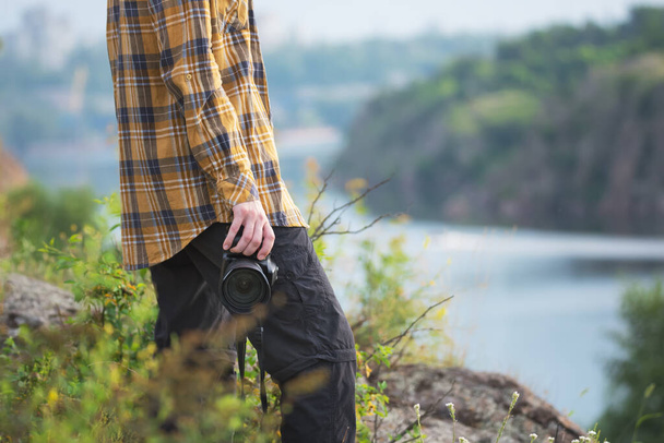 Young adult in shirt holding a camera for landscape photography. Travel concept - Photo, image