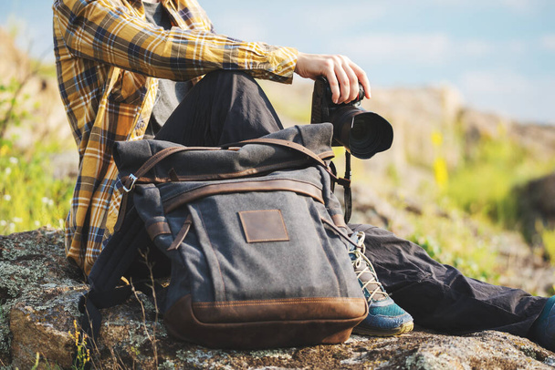 Young adult in shirt with dark gray backpack holding a camera for landscape photography. Travel concept - Фото, зображення