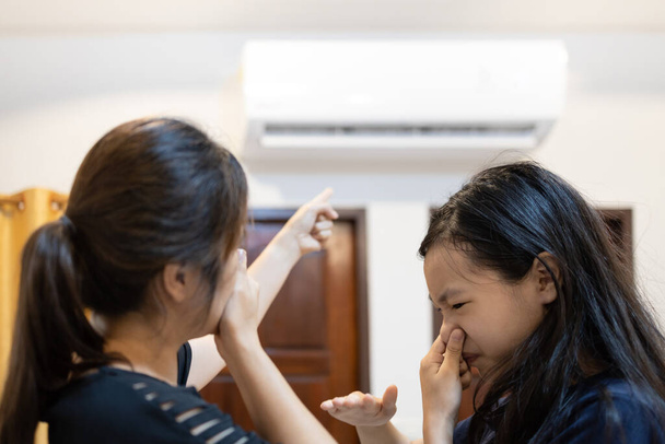 Femme asiatique et enfant fille ferment son nez, mauvaise odeur, odeur moisie de climatiseur a un problème, la poussière et la saleté entrant par la ventilation de l'air, concept de nettoyage vérifier climatiseur - Photo, image
