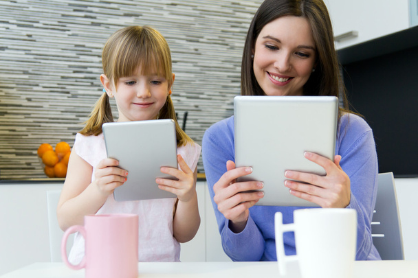 Mother and daughter using a digital tablet in kitchen - Fotoğraf, Görsel