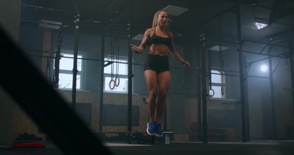 Strong muscular young woman rope skipping as warm up. Fitness concept. Young slim woman jumping with skipping rope in gym. Close-up of female feet jumping in mid air whilst using skipping rope. - Footage, Video