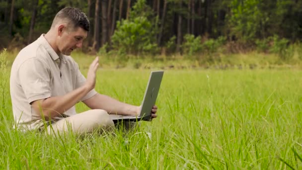 Lächelnder Mann spricht auf Video im Internet auf dem Rasen im Gras - Filmmaterial, Video