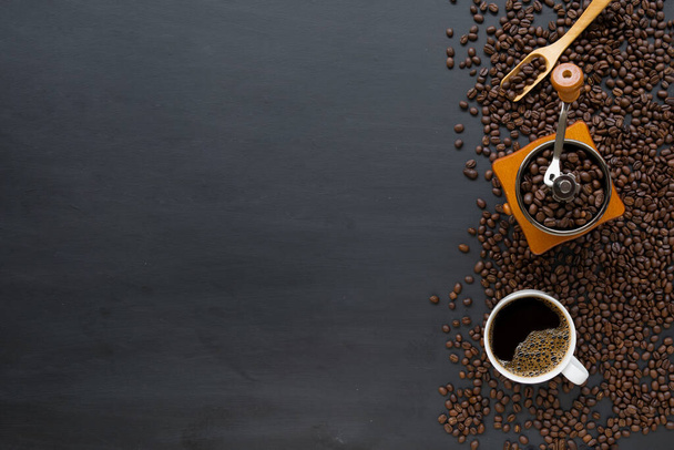 hete koffie en bonen op zwarte houten tafelondergrond. bovenaanzicht - Foto, afbeelding