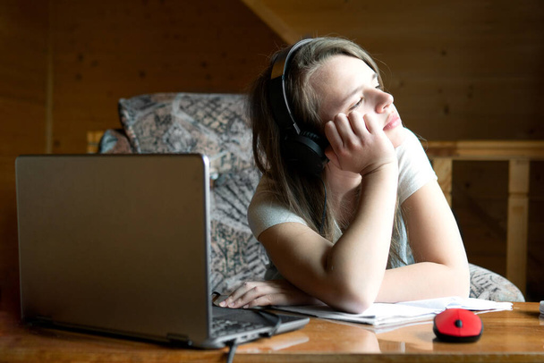 疲れて10代の女の子は、オンライン学校のウェビナー中にウィンドウを見ています。学校での過剰な学生労働の概念 - 写真・画像