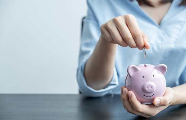 Frau steckt Münze in Sparschwein, beschleunigt Existenzgründung zum Erfolg, Sparen für Zukunftsplan und Rentenfondskonzept. - Foto, Bild