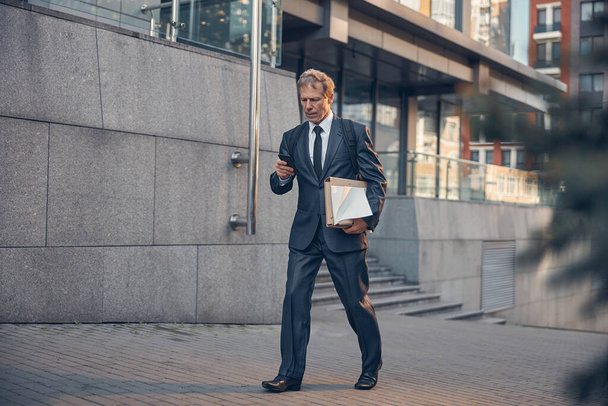 Handsome businessman walking on the street and using cellphone - 写真・画像