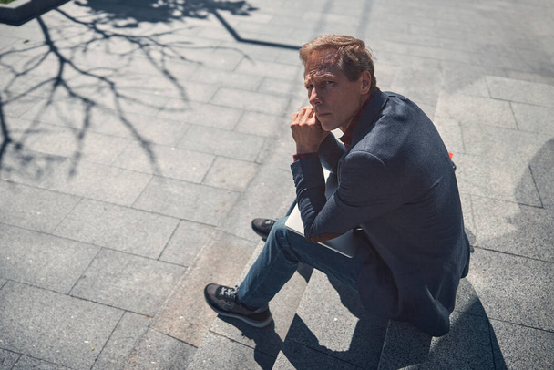 Good-looking man sitting on steps on the street - Valokuva, kuva