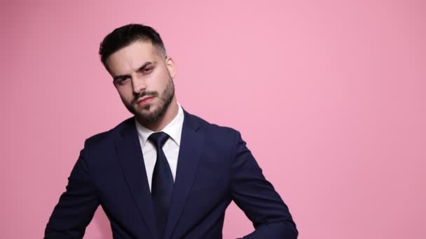 macho businessman is adjusting firmly his jacket, tie and collar then making his way out with style on pink background - Záběry, video