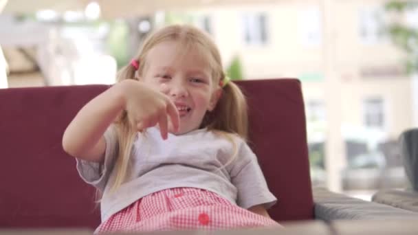 Een schattig klein meisje dat plezier heeft aan een tafel in een café - Video