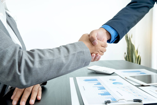 Пожатие руки два бизнес-лидера говорят о диаграммах, финансовые графики, показывающие результаты анализа и расчета стратегий планирования, бизнес-процессов построения успеха. - Фото, изображение