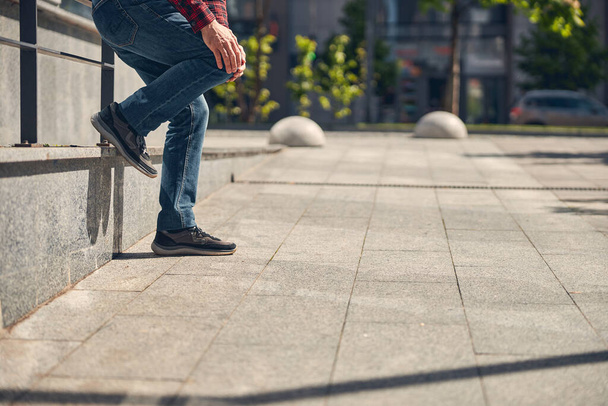 Man in jeans suffering from knee pain outdoors - Zdjęcie, obraz