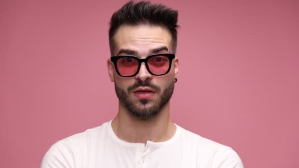 close up of a casual man looking at camera, being serious then adopting a fearful expression on his face, being surprised then happily surprised on pink background - Footage, Video
