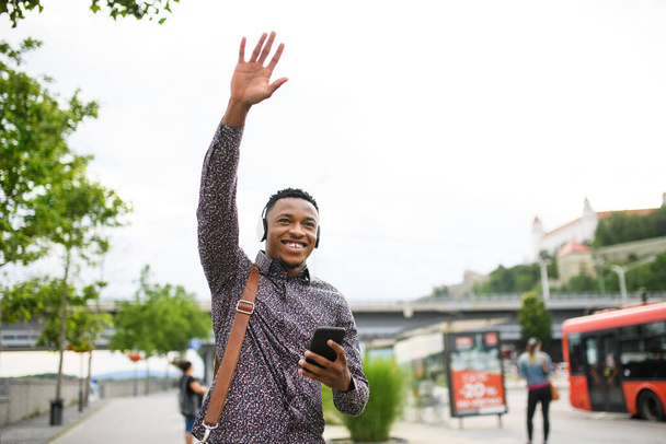 Cheerful young black man commuter outdoors in city, greeting somebody. - Foto, imagen