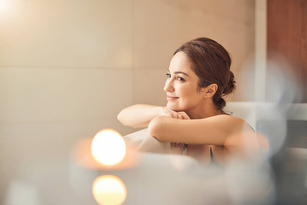 Smiling lady daydreaming in a hydromassage bath - 写真・画像
