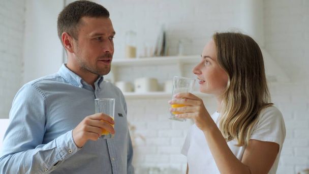 Young couple drinking fresh orange juice in home kitchen - Photo, Image