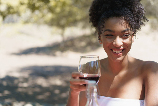 田舎の屋外で赤ワインを飲むアフリカ系女性 - 写真・画像