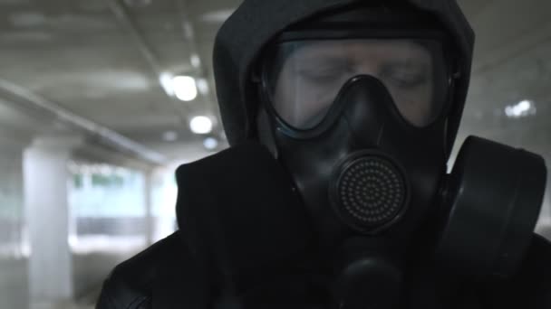 ガスマスクの男フードが長いトンネルを通って地下を歩く黒いジャケット - 映像、動画