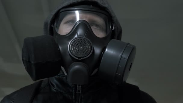man met gasmasker, zwarte jas met kap lopend door lange tunnel, onderdoorgang - Video