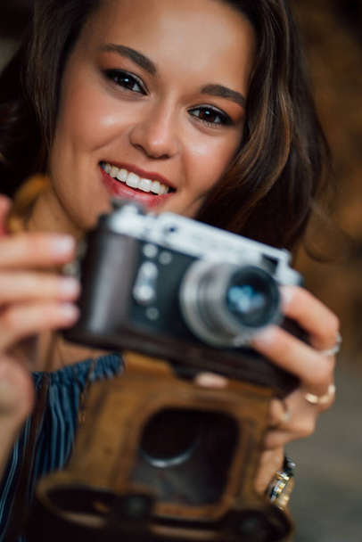 close-up of beautiful brunette girl  with retro camera in hands. - Фото, изображение