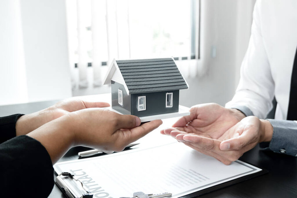 不動産仲介業者は、家を借りて住宅保険を購入する契約に従って署名を完了した後、新しい所有者に家を引き渡すホーム保険の概念. - 写真・画像