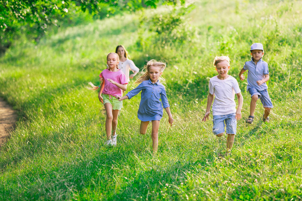 Kids, children running on meadow in summers sunlight - Foto, Imagen