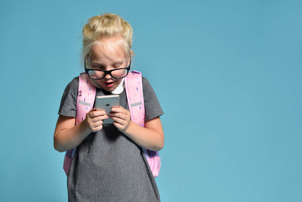 Young schoolgirl emotionally plays with smartphone and impairs vision - Photo, image